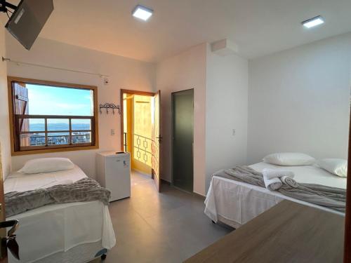 a bedroom with two beds and a window with a view at Pousada Recanto das Estrelas in São Thomé das Letras