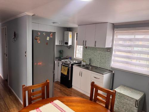 a kitchen with white cabinets and a table and a refrigerator at Cabaña en Malalcahuello in Malalcahuello