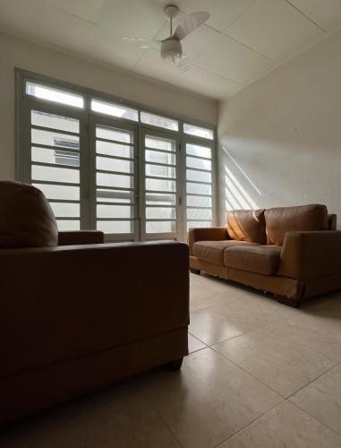 a living room with two brown couches and windows at Casa grande e arejada ao lado da praia! in Itanhaém