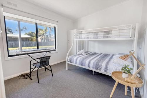 Un dormitorio con una cama y un escritorio y una ventana. en Seaside Escape, en Lakes Entrance