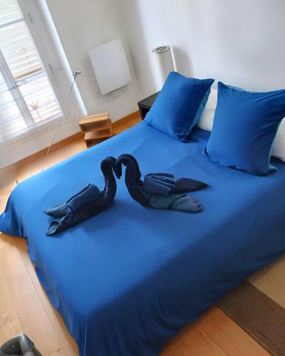 deux cygnes noirs assis sur un lit bleu dans l'établissement Pittoresquia Paris Gare de l'Est, à Paris