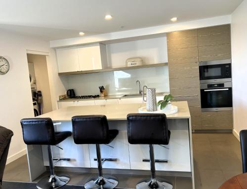 a kitchen with a counter with three bar stools at PROMENADE TOWERS 2 Bedroom Apartment with City Views on the Geelong Waterfront - 506 in Geelong