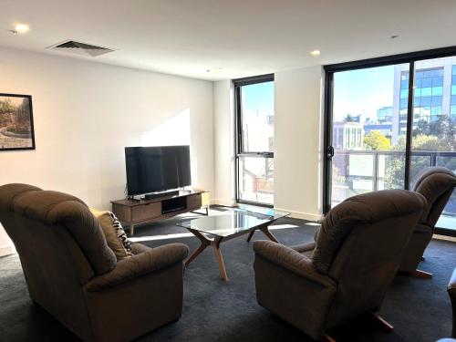 a living room with two chairs and a television at PROMENADE TOWERS 2 Bedroom Apartment with City Views on the Geelong Waterfront - 506 in Geelong