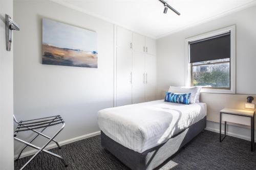 a bedroom with a bed and a desk and a window at Nightcap at Riverside Hotel in Launceston