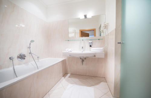 a bathroom with a tub and a sink and a bath tub at Hotel Grüner Baum in Zell am See