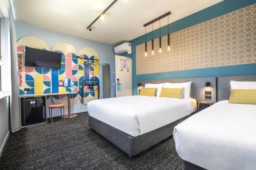 a hotel room with two beds and a tv at Royal Hotel by Nightcap Social in Melbourne