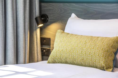 a bed with a yellow pillow next to a window at Royal Hotel by Nightcap Social in Melbourne