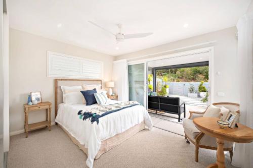 a white bedroom with a bed and a window at The Lookout in Corlette