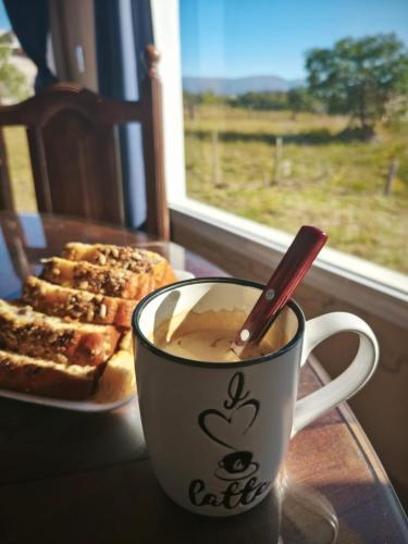 a cup of coffee next to a plate of bread at Altura serrana in Villa Yacanto