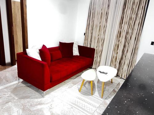 un soggiorno con divano rosso e 2 tavoli di حي الواحات a El Aouina Station