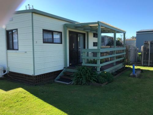 a tiny house with a porch and a deck at Golden Terrace Holiday Park in Lakes Entrance