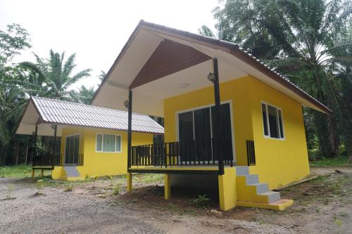 a small yellow house with a porch at Khao Sok Palmview Resort in Khao Sok