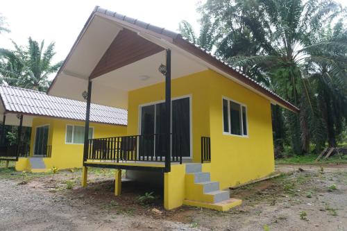 a small yellow house with a porch and stairs at Khao Sok Palmview Resort in Khao Sok