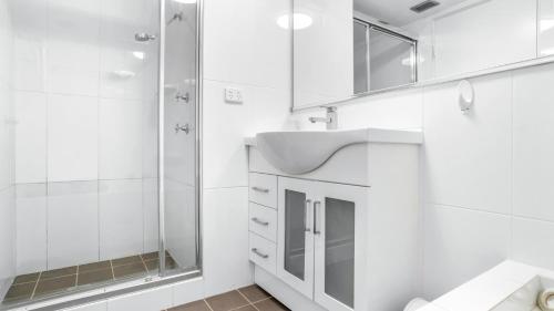 ein weißes Badezimmer mit Waschbecken und Dusche in der Unterkunft Beachpoint 402 in Forster