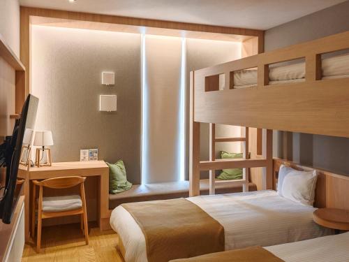 a bedroom with a bunk bed with a desk and a desk at ホテル ログイン ニセコ in Kutchan