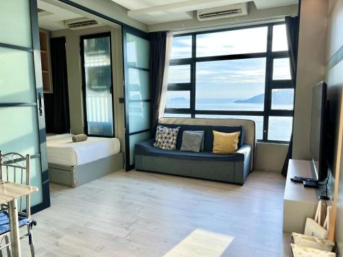 a room with a couch and a bed and windows at Margo Home - Jesselton Quay in Kota Kinabalu