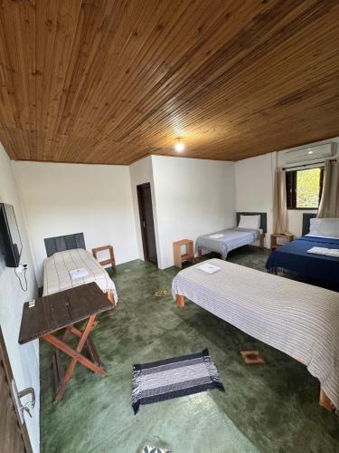 a room with two beds and a wooden ceiling at Pousada Recanto Das Gerais in Carmo do Rio Claro