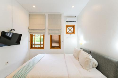 a white bedroom with a bed and a tv at Djajanti House in Semarang