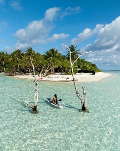 a person in a kayak in the water near a beach at Kirulhiya Maldives - Omadhoo in Omadhoo
