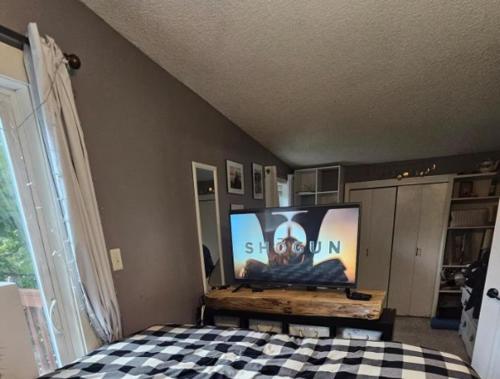 a bedroom with a bed with a flat screen tv at Last Frontier Lodge - Forest, Mountain, Ocean Views in Kodiak