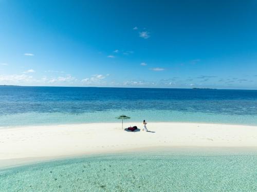 a person standing under an umbrella on a beach at Kirulhiya Maldives - Omadhoo in Omadhoo