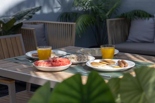 a table with plates of food and two glasses of orange juice at Kirulhiya Maldives - Omadhoo in Omadhoo