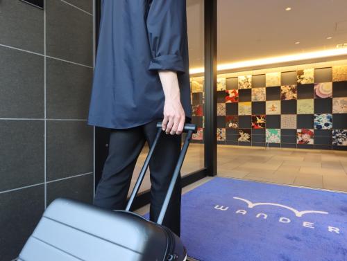 a person holding a suitcase in a room at Wander Kyoto Nanajo in Kyoto