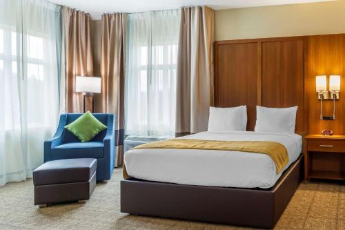 a bedroom with a bed and a blue chair at Comfort Inn & Suites Lakewood by JBLM in Lakewood