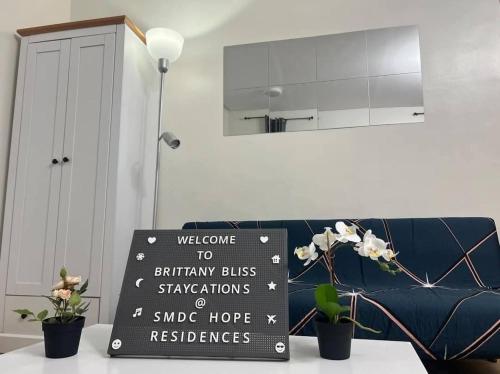 a sign in front of a couch in a living room at Brittany Bliss Staycations at SMDC HOPE RESIDENCES in Trece Martires