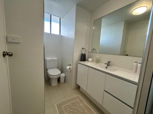 a bathroom with a toilet and a sink and a mirror at Beachfront Oceanic 5 in Forster