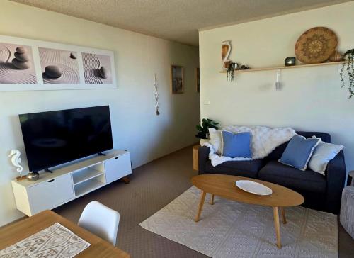 a living room with a couch and a flat screen tv at Beachfront Oceanic 5 in Forster