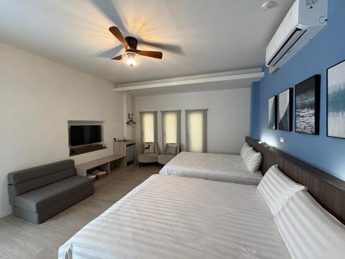 une chambre avec deux lits et un ventilateur de plafond dans l'établissement 日安蝸牛, à Tainan