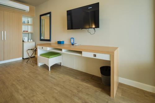 a room with a desk with a television on a wall at Phuket Boat Quay Hotel Panwa Beach in Panwa Beach