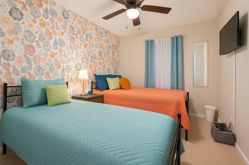 a bedroom with two beds and a flat screen tv at Spacious 4BR House Sleeps 9 Outdoor Lounge with Fire Pit plus Games in Raleigh