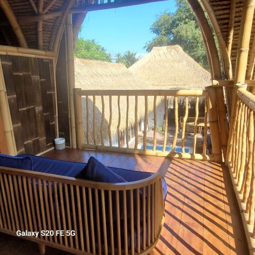 a balcony with a bench on a wooden deck at Tricky Trees Lodges in Gili Air