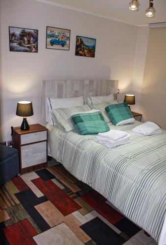 a bedroom with a bed with green pillows and a table at Auroras apartment in Santiago