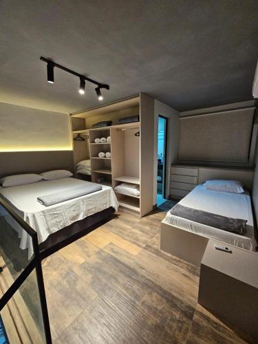 a bedroom with two beds and a large window at Lofts 4 Elementos - Ar - Martim de Sá - Caraguatatuba in Caraguatatuba
