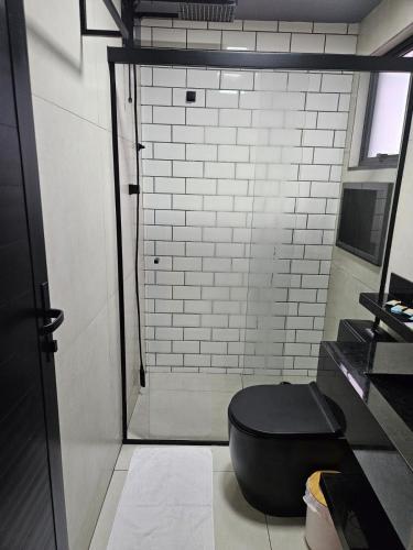 a bathroom with a toilet with a black seat at Lofts 4 Elementos - Ar - Martim de Sá - Caraguatatuba in Caraguatatuba