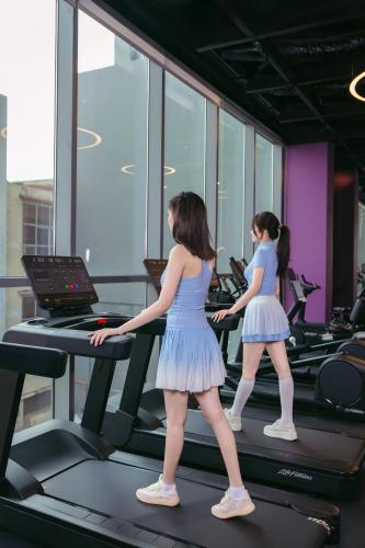 two women walking on a treadmill in a gym at Wink Hotel Can Tho Ninh Kieu Wharf - 24hrs Stay & Rooftop Pool Bar in Can Tho