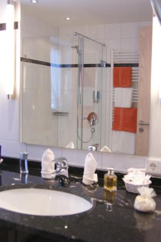 a bathroom with a sink and a shower with a mirror at Hotel Landhaus Feldmeier ***S in Oberammergau