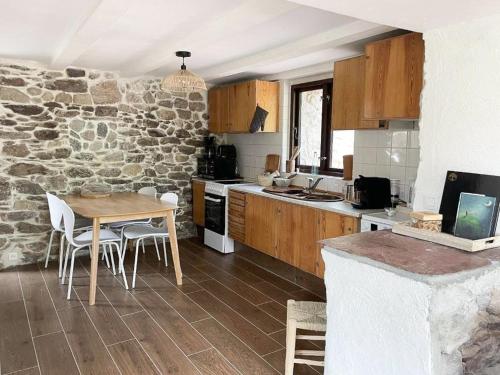 a kitchen with a table and a stone wall at 17Th Century Renovated Barn In Valdeblore in Valdeblore