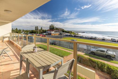 balcón con mesa de madera y vistas al océano en Ebbtide 8, en Forster