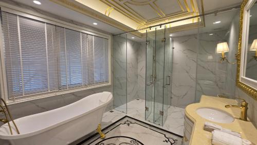 a bathroom with a tub and a glass shower at Champa Palace Hotel in Pakse