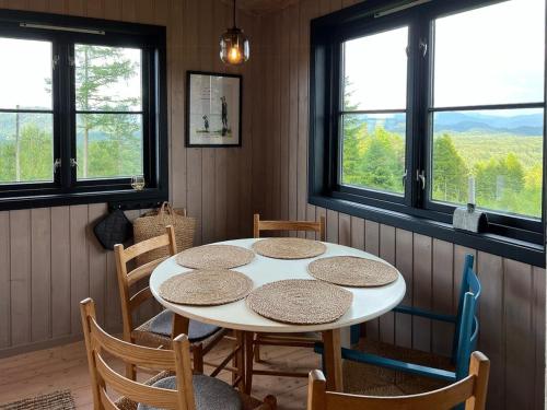 een tafel en stoelen in een kamer met ramen bij Panoramic Cabin With Forest And Mountain Views in Sveio
