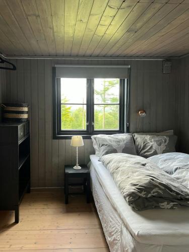 a bedroom with a bed and a window and a lamp at Panoramic Cabin With Forest And Mountain Views in Sveio