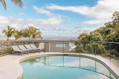 a swimming pool on a balcony with two chairs at Tranquil Noosa at its best Beach, Bush, Good Food. in Noosa Heads
