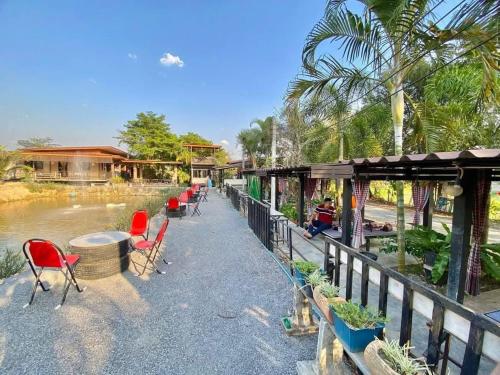 a row of chairs and tables next to a river at Hug Wang Homestay in Ban Nong Chaeng