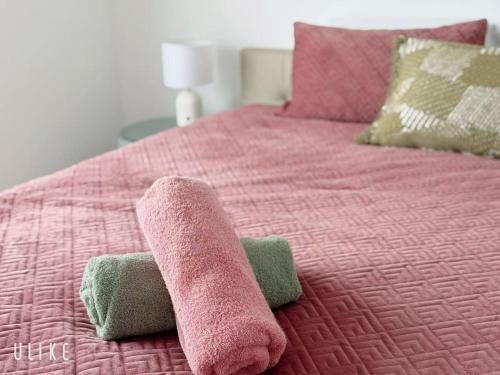 a pink bed with a pair of towels on it at Cozy 4B Villa close to Theme Park in Pimpama