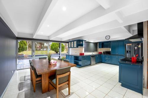 a large kitchen with blue cabinets and a wooden table at Perfect Family Getaway in Cranbourne South in Devon Meadows