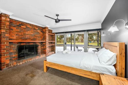a bedroom with a brick fireplace and a bed at Perfect Family Getaway in Cranbourne South in Devon Meadows